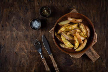 Baked potato in a plate on a wooden background, top view