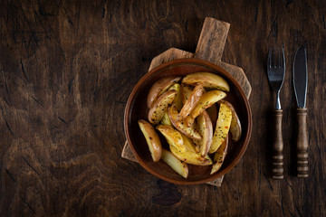 Baked potato in a plate on a wooden background, top view