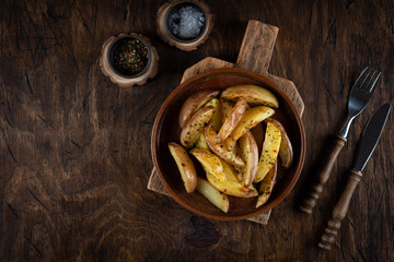 Baked potato in a plate on a wooden background, top view