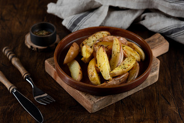 Baked potato in a plate on a wooden background, top view