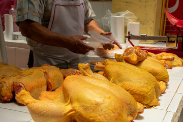 Pollería en mercado mexicano, con pollos crudos siendo partidos por el carnicero