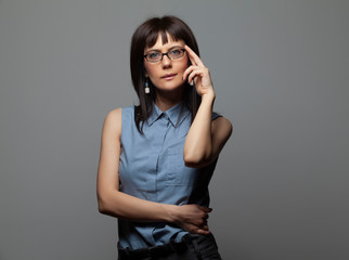 Portrait of young beautiful woman with glasses on gray background 