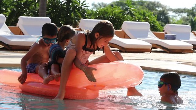 Children at the pool playing with inflatable mattress