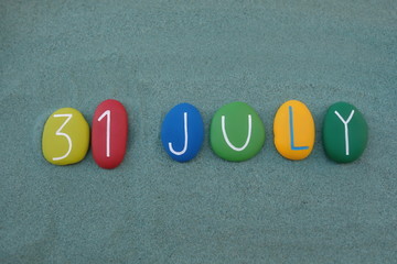  31 July, calendar date composed with multi colored stones over green sand