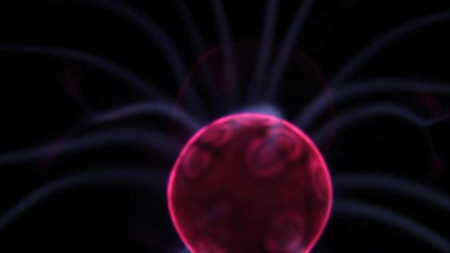 Closeup of a steady plasma ball red center with electric blue rays moving around against pitch black background