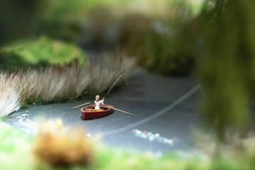 The layout of the city. Model of a pond with a boat and a fisherman. A fisherman catches a fish.