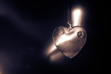Valentines Day Concept. Glass transparent heart on dark. Crystal heart in the dark, glass heart glows, glass painting, black background