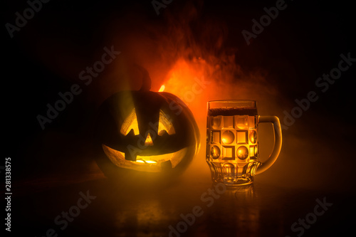 Glass of cold light beer with pumpkin on a wood background for Halloween. Glass of fresh beer and pumpkin on a dark toned foggy background