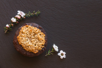 chocolate and coconut cake with white manuka flowers on black slate serving board
