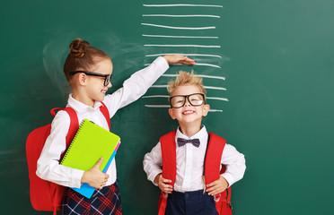 concept of   development in education. children boy and girl students measure growth about school blackboard.