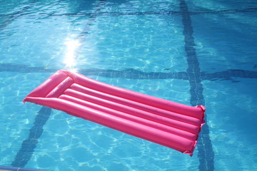 Pink air mattress in the swimming pool on water