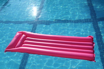 Pink air mattress in the swimming pool on water