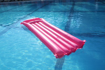 Pink air mattress in the swimming pool on water