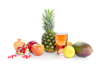 Mango, pineapple, lemons, apples, pomegranates and fruity juice on white background close-up.