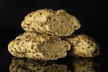Group of one whole two halves of fresh cereal baguette isolated on black glass