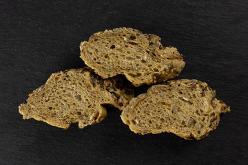 Group of three slices of fresh cereal baguette flatlay on grey dark stone
