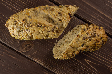 Group of two halves of fresh cereal baguette flatlay on brown wood