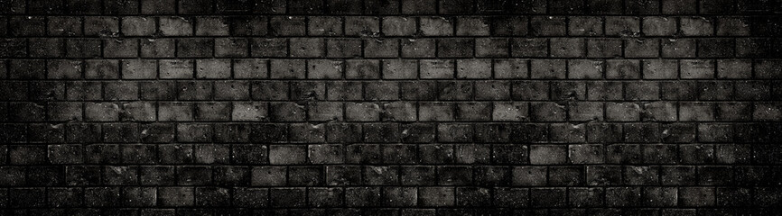 Old and weathered grungy black dark concrete block brick wall texture background abandoned house with holes and cracks and vignetting as scary large panorama wide banner background.