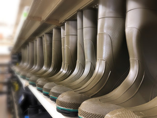 Green rubber boots in a long row. Classic work shoes for farmers and gardeners.