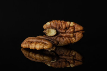 Group of two whole bright fresh brown pecan nut half isolated on black glass