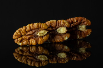 Group of three whole fresh brown pecan nut half in row isolated on black glass