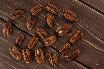 Lot of whole fresh brown pecan nut half flatlay on brown wood