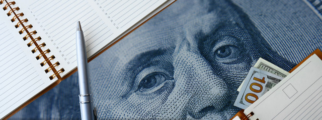 Empty notebook paper page with hundred dollar bills. Mock up book blank on a blue background With a picture of Franklin. 