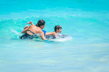 Loving mom teaches young boy to bodysurf