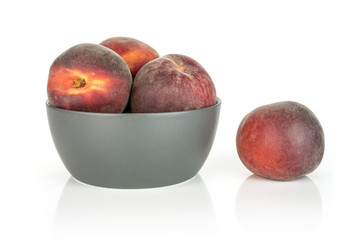 Group of four whole fresh red peach one is aside and the rest is in a gray ceramic bowl isolated on white background