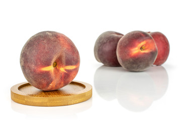 Group of four whole fresh red peach on a round bamboo coaster isolated on white background