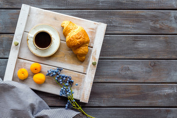 Breakfast on the tray with croissant, coffee and fruit on wooden background top view mockup