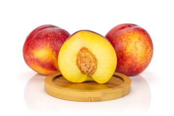 Group of two whole one half of fresh red nectarine on a round bamboo coaster isolated on white background