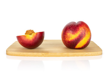 Group of one whole one half of fresh red nectarine on a bamboo cutting board isolated on white background