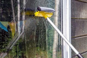 washing Windows, cleaning glasses and surfaces. yellow-white telescopic washing brush cleanly...