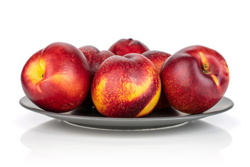 Lot of whole fresh red nectarine on a gray ceramic plate isolated on white background