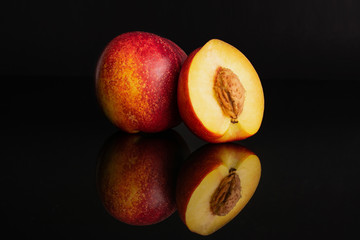 Group of one whole one half of fresh red nectarine isolated on black glass