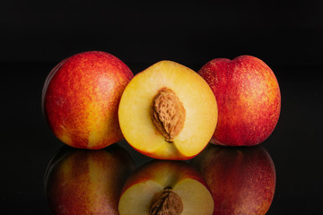 Group of two whole one half of fresh red nectarine isolated on black glass
