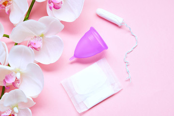 Various sanitary products on pastel pink background. Pad, menstrual cup, tampons. Perion concept. Flat lay, top view. Copy space