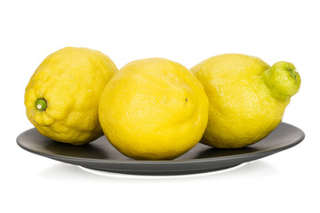 Group of three whole fresh yellow lemon on a grey ceramic plate isolated on white background