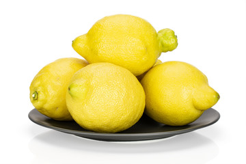 Group of four whole fresh yellow lemon on a grey ceramic plate isolated on white background