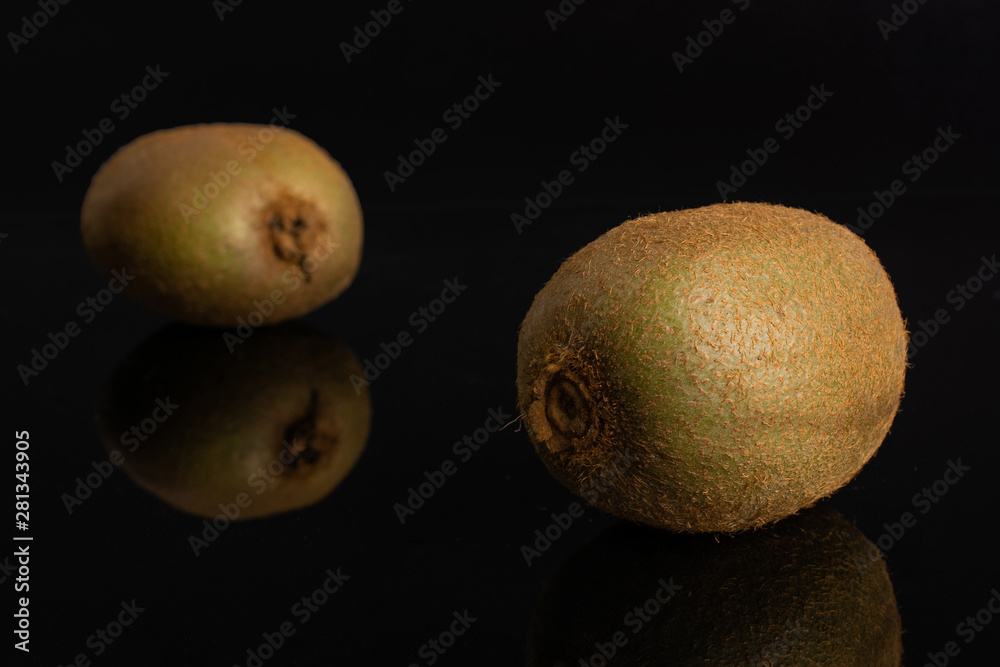 Wall mural group of two whole fresh green kiwifruit actinidia deliciosa one is in the front isolated on black g