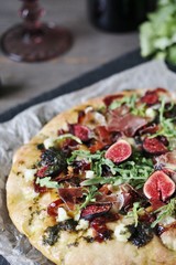 pizza with figs and prosciutto. different cheeses and gorgonzola, basil dressing with olive oil, onion marmalade (caramelized onion), arugula, balsamic sauce. close-up.