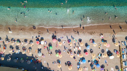 Aerial top view of the sandy beach and blue color sea with sunshade on the sandy beach