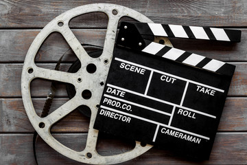 Go to the cinema with film type and clapperboard on wooden background top view