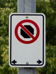 no stopping street sign with bushes in background 