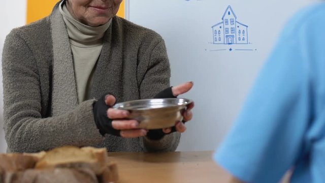 Aged homeless woman accepting food in volunteer center, social insecurity, aid