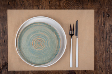 Empty plate with fork and knife on colored wooden background, top view, copy space, mock-up