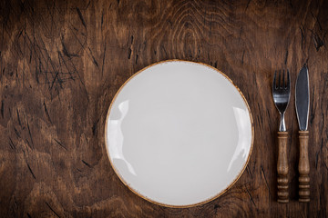 Empty plate with fork and knife on colored wooden background, top view, copy space, mock-up