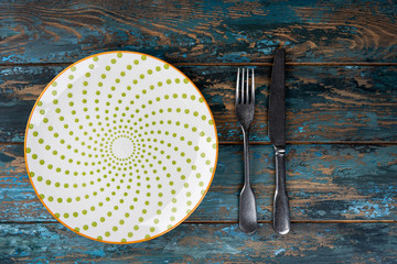 Empty plate with fork and knife on colored wooden background, top view, copy space, mock-up