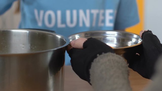Volunteer pouring soup for homeless person in social support center, assistance